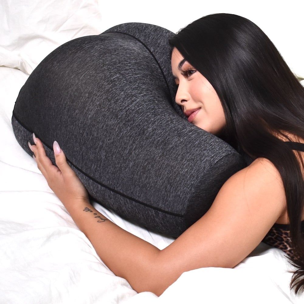 Stomach sleeper using The Buttress Pillow - face resting between thighs with breathing gap for comfortable stomach sleeping position